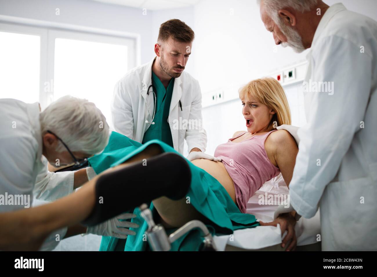 In the hospital woman in labor pushes to give birth, obstetricians assisting Stock Photo
