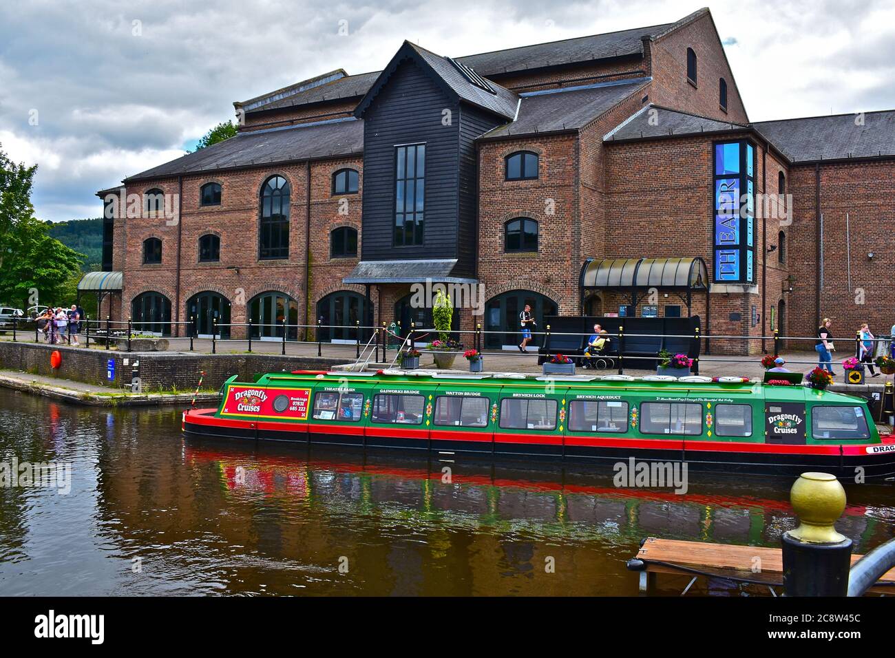 A street view of Theatr Bryncheiniog, located on the side of the central canal basin in Brecon town centre. Canal cruise boat at moorings Stock Photo