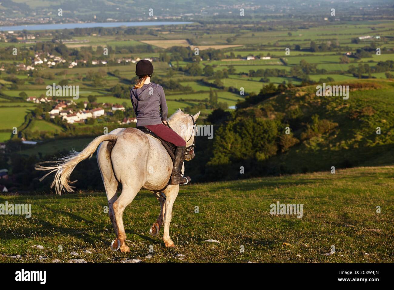 A horse rider on Crook Peak, in the Mendip Hills, with a view of the Somerset Levels beyond, Somerset, Great Britain. Stock Photo