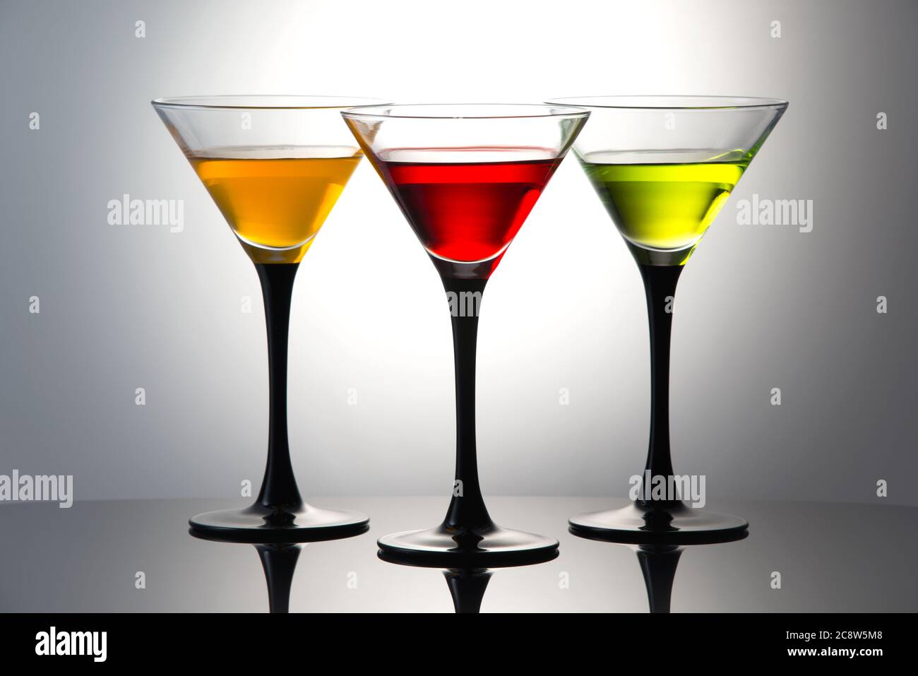 Coloured drinks in martini glasses, cocktails with orange, red and green liqueurs Stock Photo