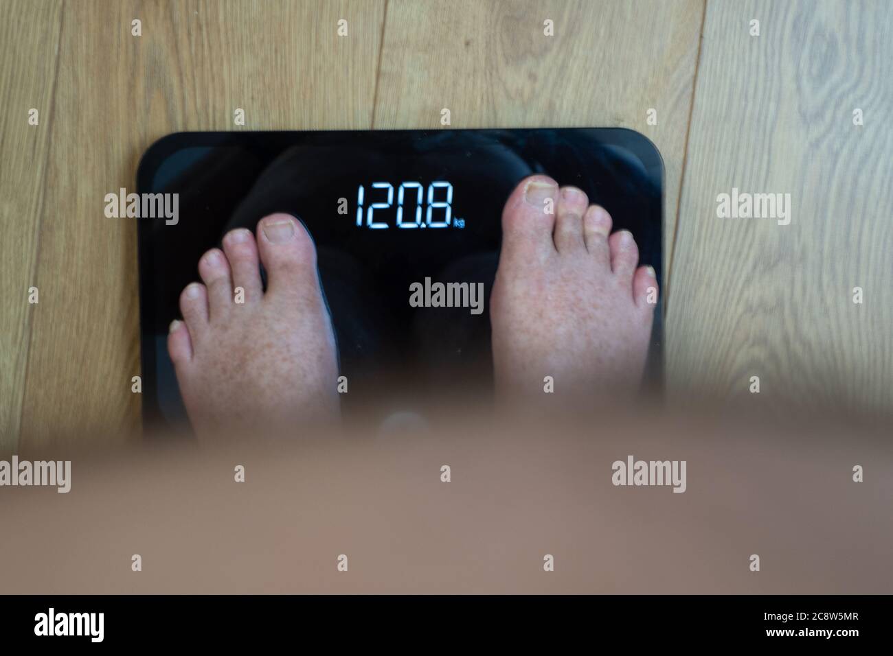 https://c8.alamy.com/comp/2C8W5MR/obese-mans-point-of-view-looking-at-his-feet-and-his-weight-on-the-weighing-scales-2C8W5MR.jpg