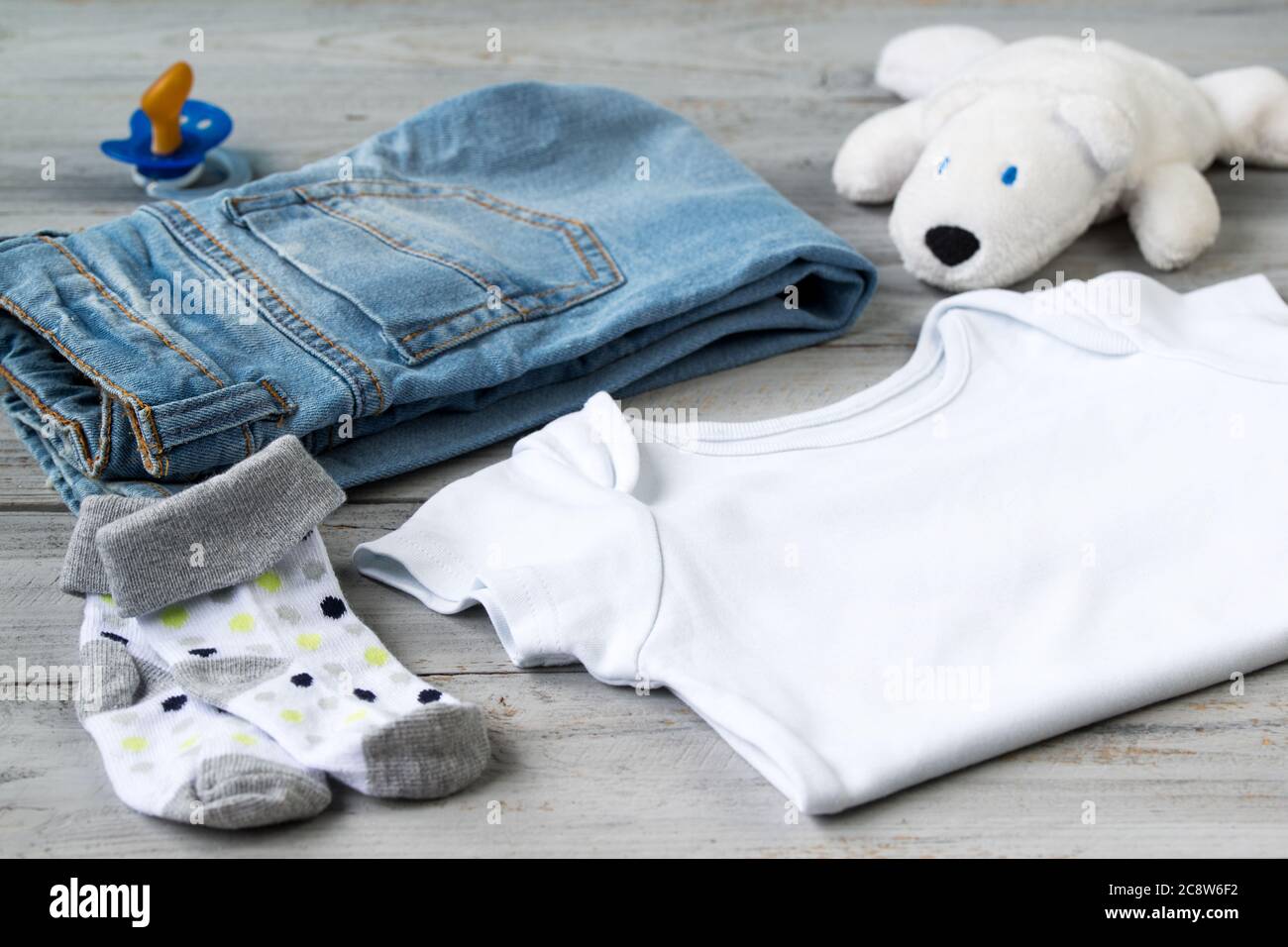 Baby clothes and accessories with white bear toy on a wooden background Stock Photo