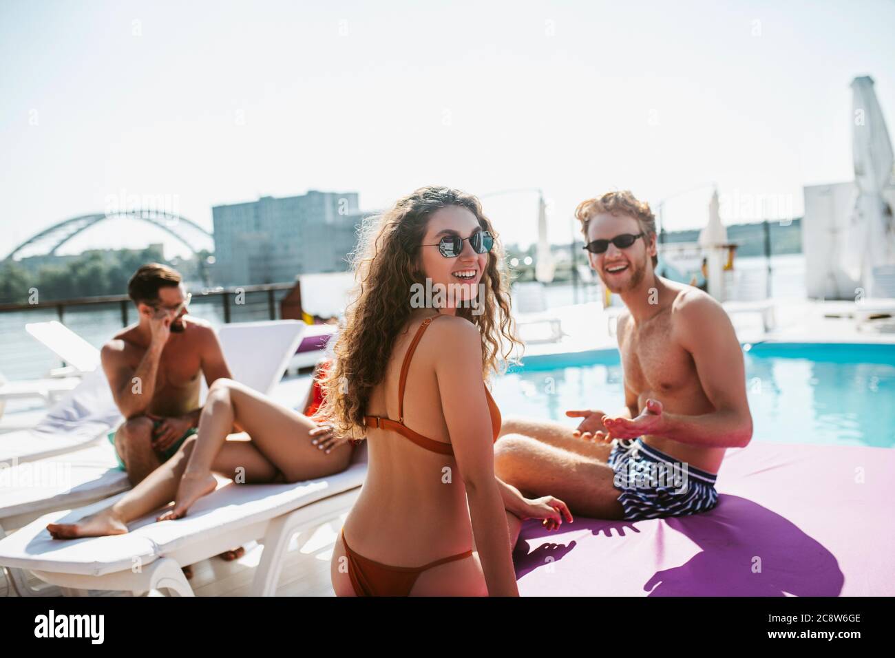 Long-haired woman and red-haired man talking near the swimming pool Stock Photo