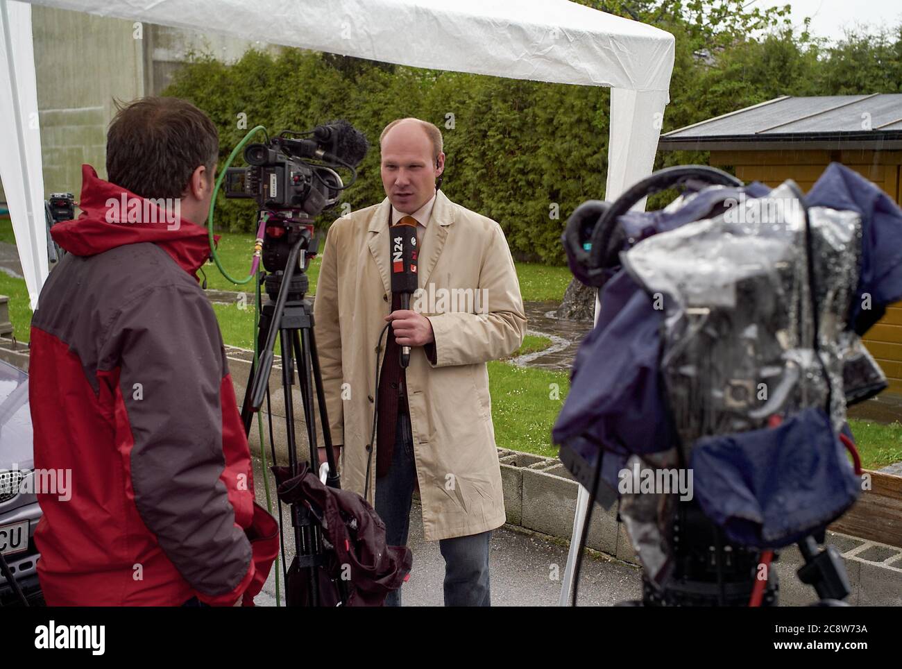 Amstetten, Austria - April 29 2008: TV News Reporter Moderating in the Pouring Rain on the Fritzl Cellar Case. Stock Photo