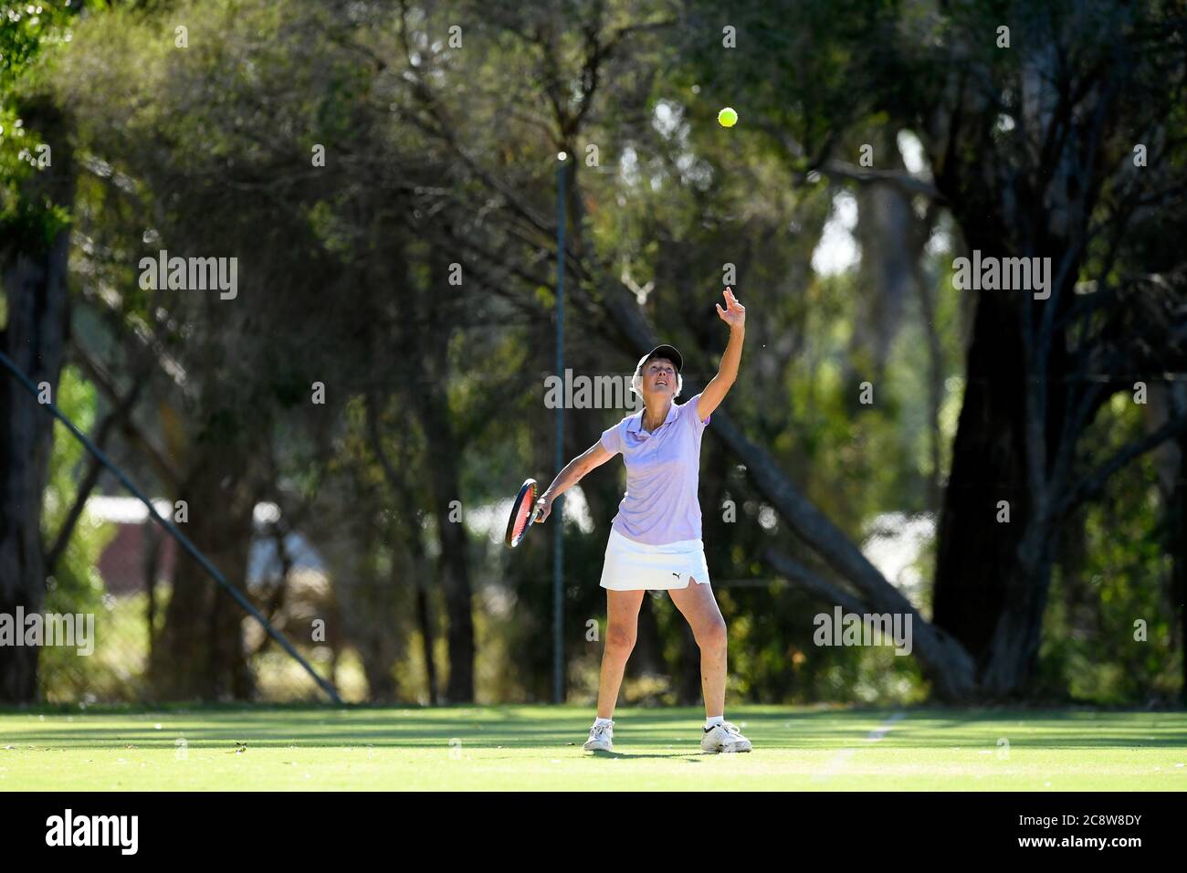 An older lady stretches for the tennis ball during a local tennis tournament in Victoria Australia Stock Photo