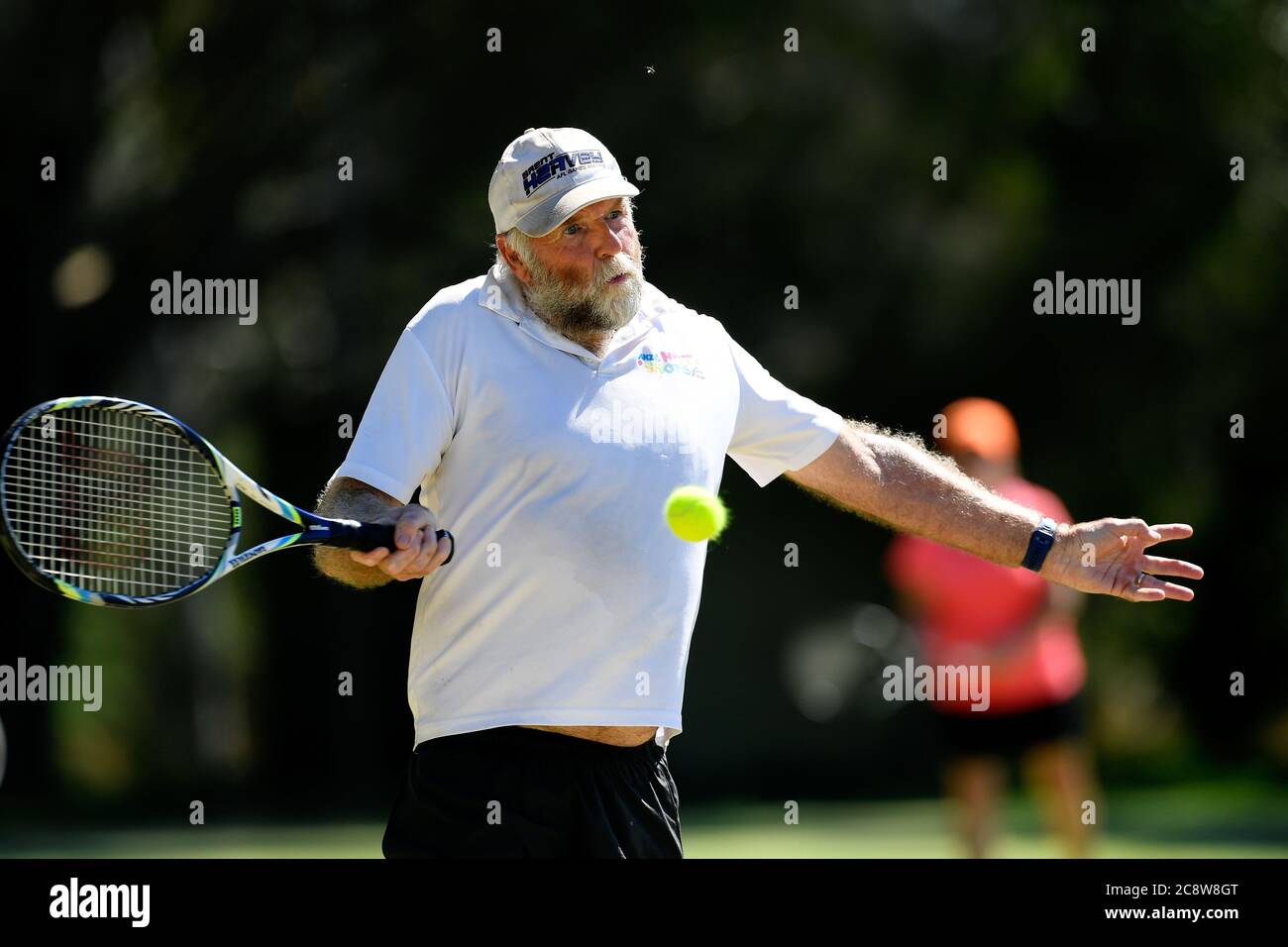 Grass roots sport. an older man prepares to take a shot during a tennis match, Benalla, Victoria, Australia Stock Photo