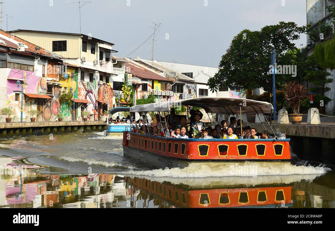 School children soak up the kaleidoscope of brightly painted buildings that stretch for miles aside the Melaka River. Stock Photo