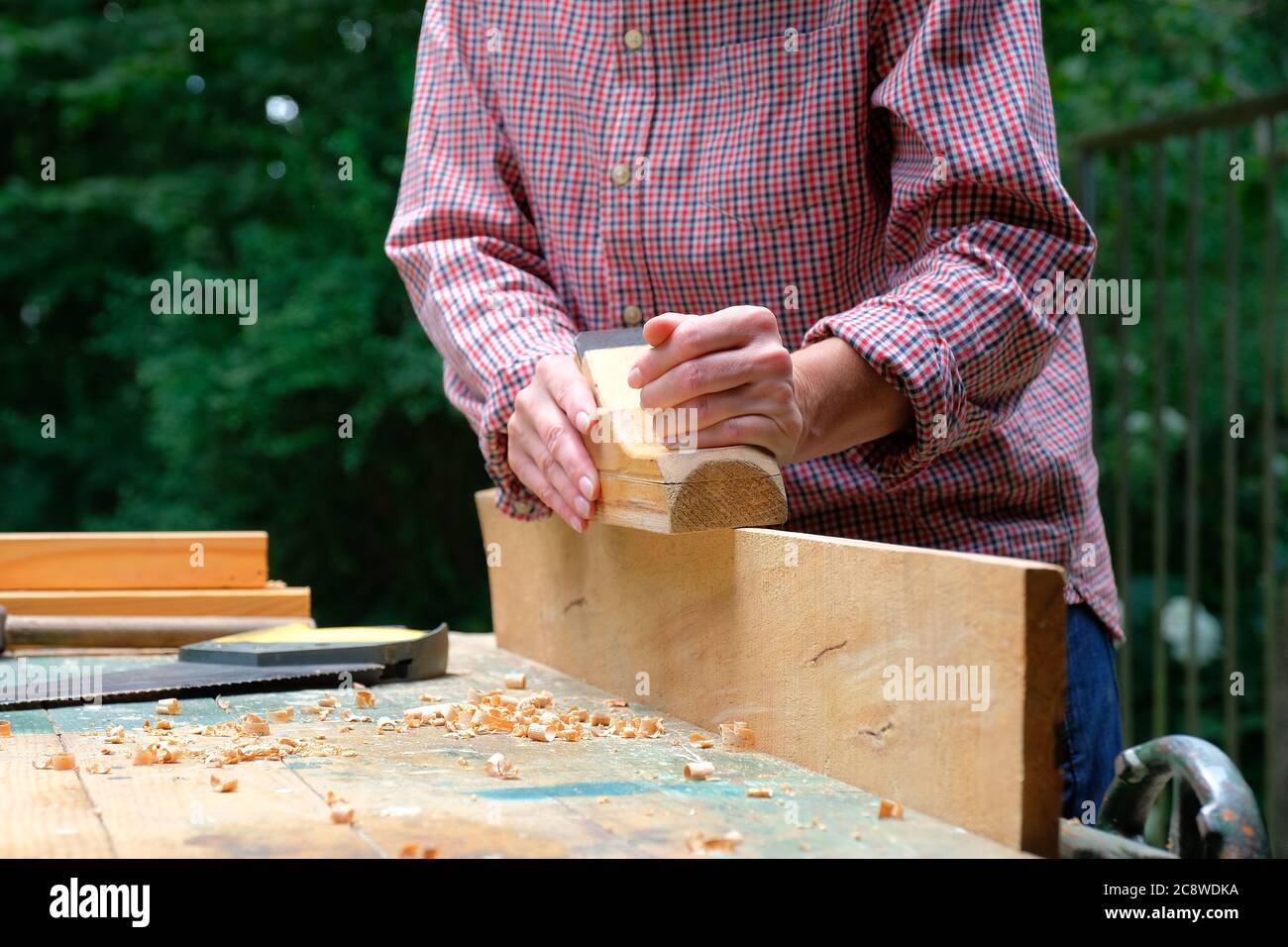 Craftswoman works with a wood planer outdoors. DIY, woodwork concept