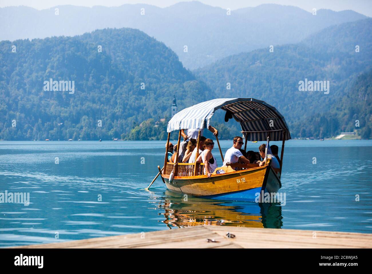 Ein Boot / ein Schiff voll mit Touristen / Passagieren schwimmt auf dem Bleder See in Richtung Ufer. Es kommt gerade von der Insel Blejski otok. | usage worldwide Stock Photo