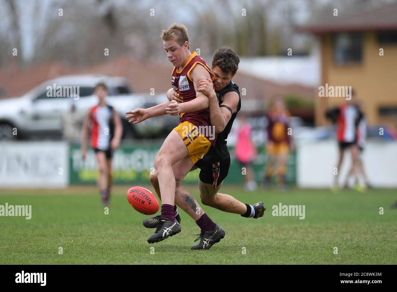 A Myrtleford Saints' player tackles Wangaratta Imperials Will Ashton as he attempts to drop kick the football. Stock Photo