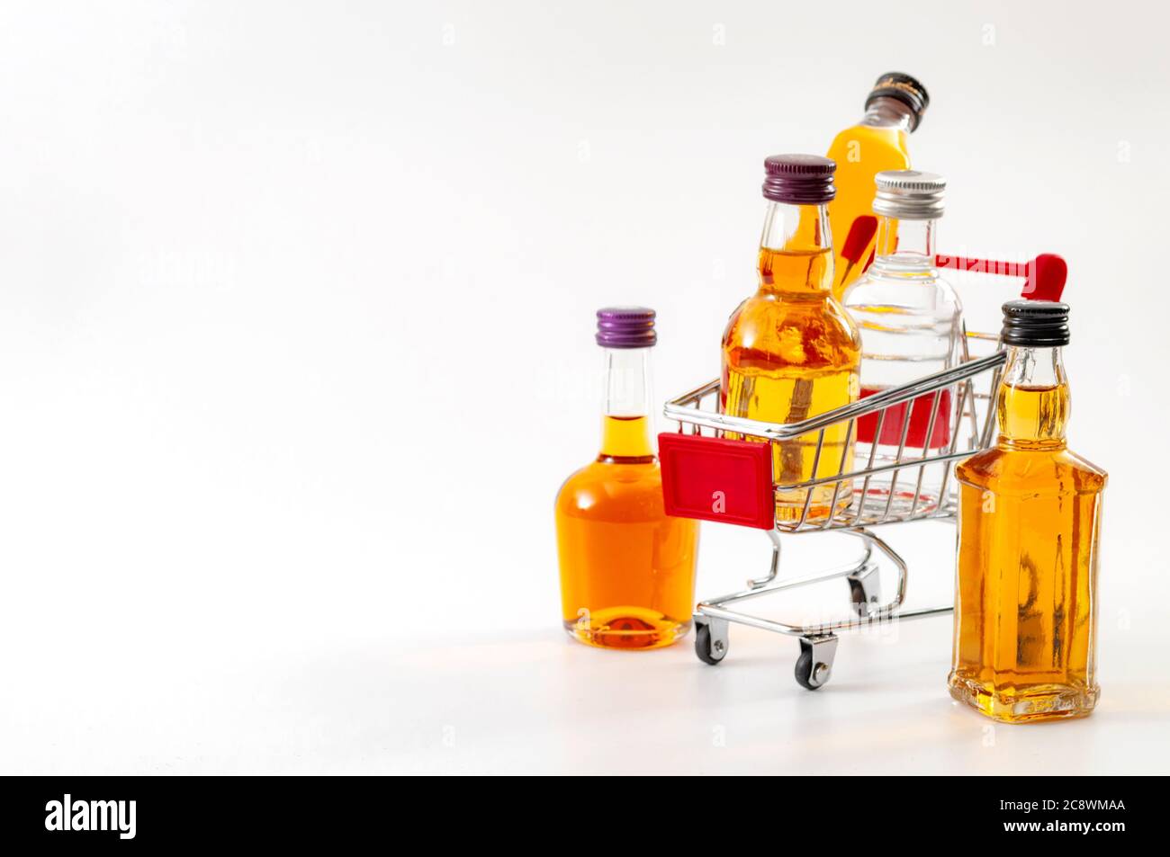 Buy booze, shopping the liqueur aisle and purchase of alcoholic beverages concept theme with mini bottles of alcohol in a small supermarket cart isola Stock Photo