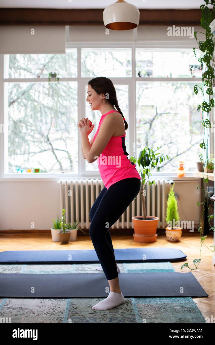 Beautiful Young Woman Exercising Pilates, Yoga, Fitness at Home Looking at the Laptop Stock Photo