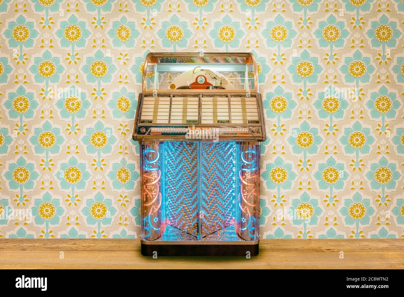 Colorful vintage jukebox in front of retro flower wallpaper on a wooden floor Stock Photo