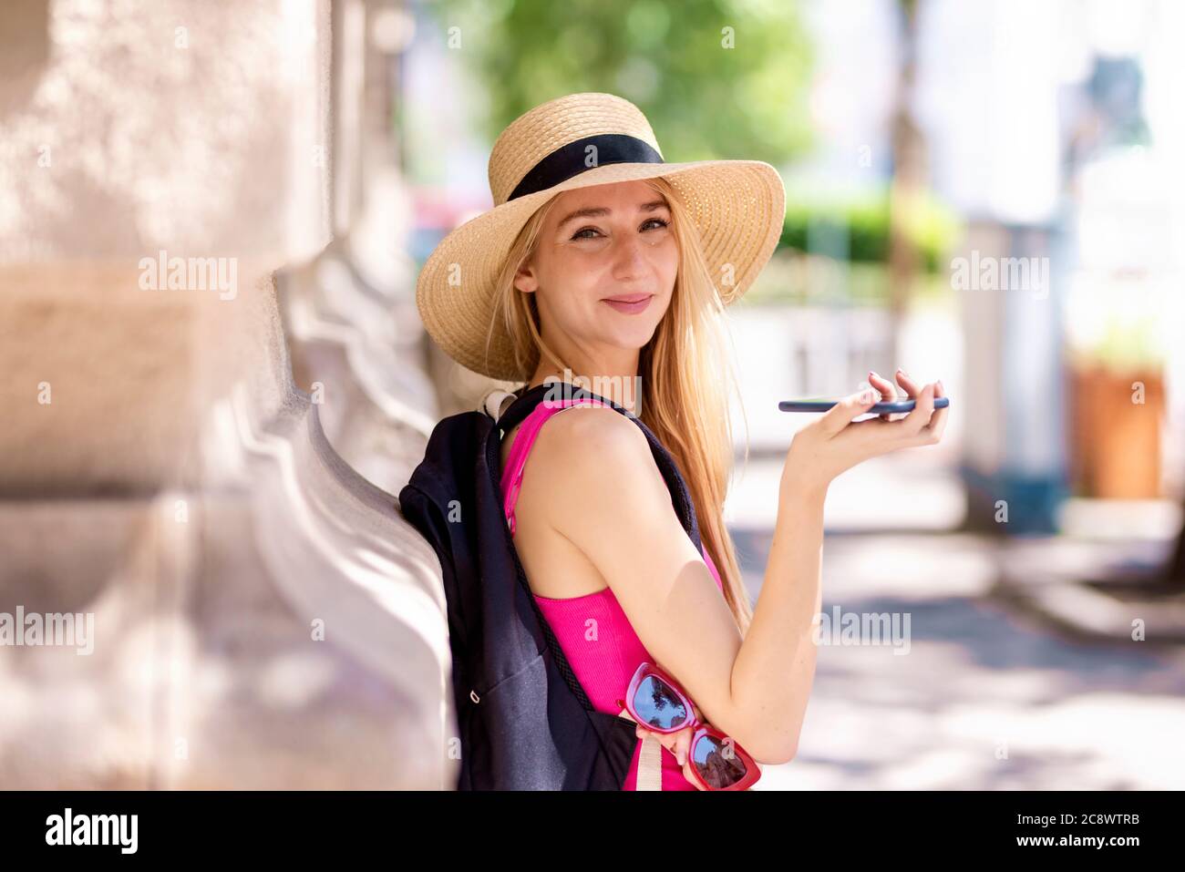 Close-up portrait shot of beautiful young woman wearing straw hat while  standing on the street and having a call Stock Photo - Alamy