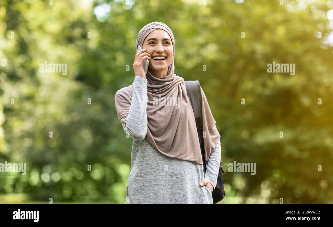 Happy muslim woman in hijab talking on phone while walking Stock Photo ...