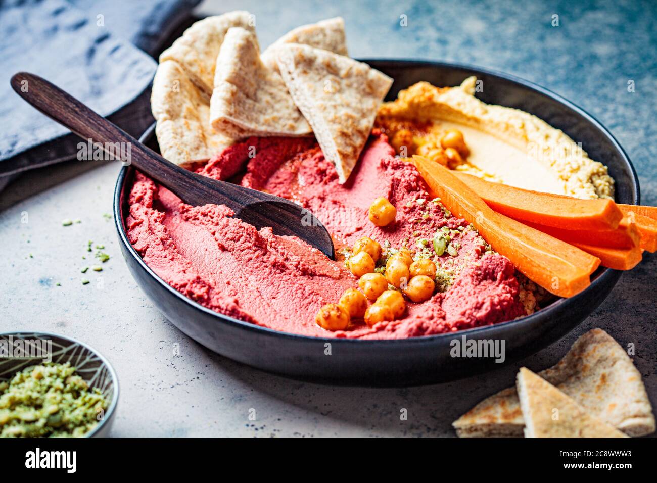 Beetroot and classic hummus in black dish with carrots and pita bread