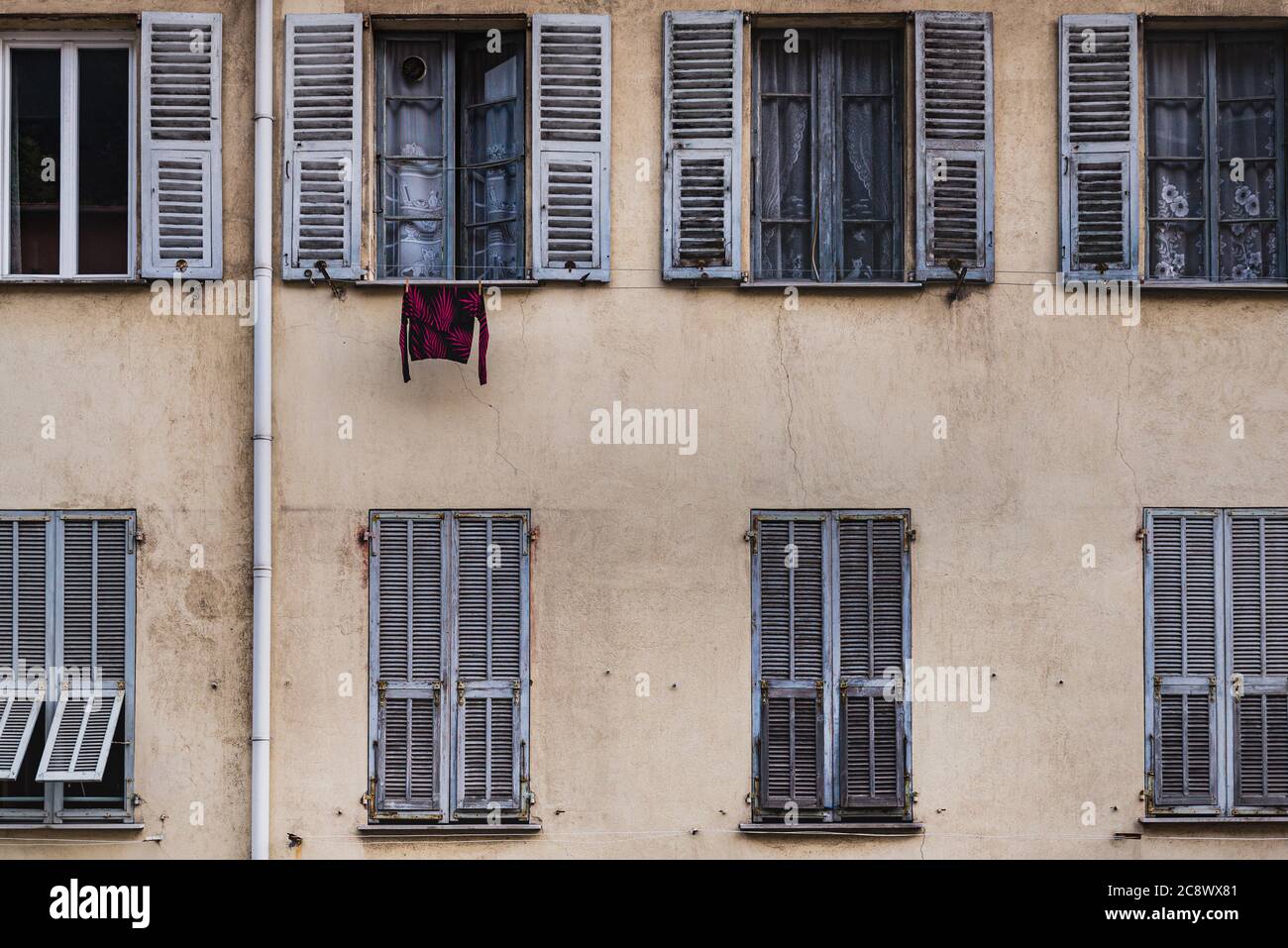 Hanging shirt at a window on a traditional old French facade with rows of windows (jalousie) conveys a downtown lifestyle and neighbourhood privacy Stock Photo