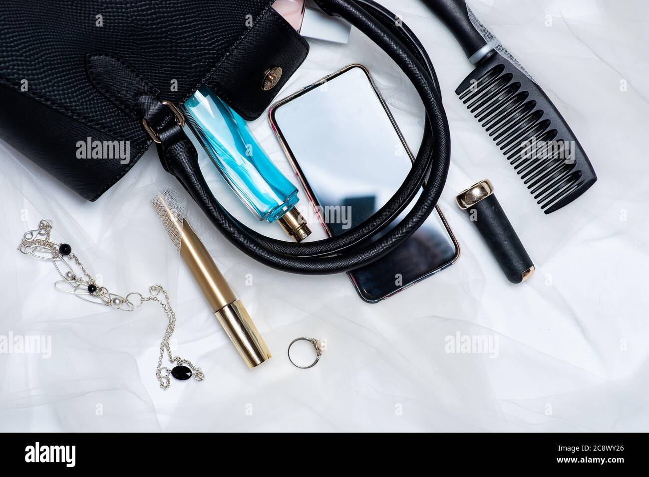Various makeup and cosmetic products falling out of an female bag tabletop flat lay with copy space Stock Photo