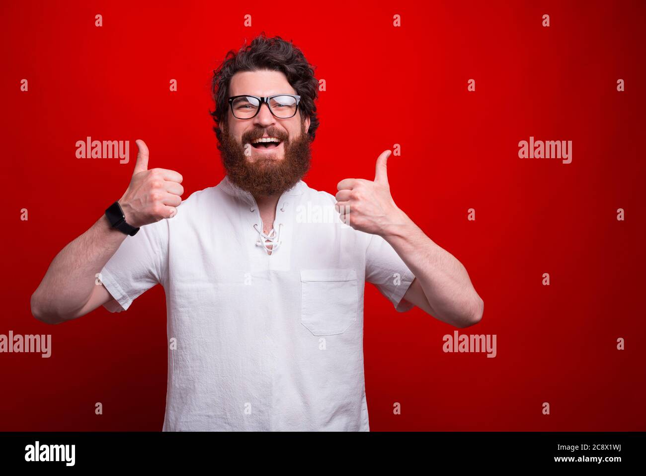 Photo of cheerful young man with beard showing thumbs up. Stock Photo