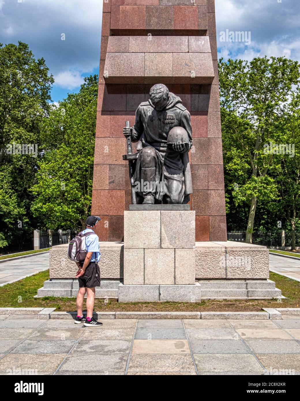 Bronze Kneeling soldier sculpture in front of abstract granite flag at Soviet War Memorial in Treptow Park, Berlin, Germany Stock Photo