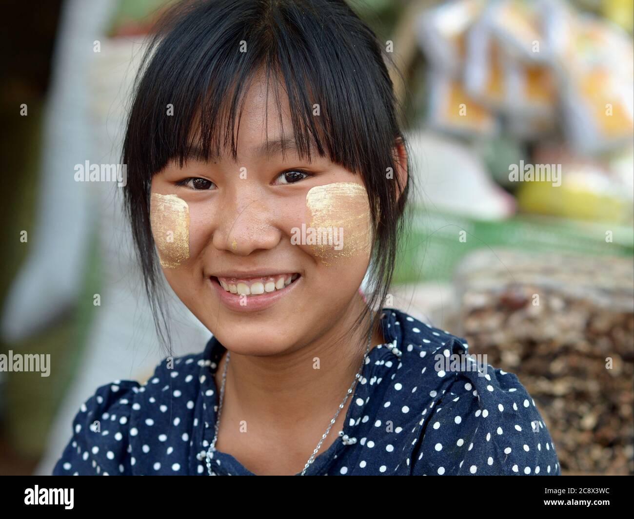 Young Burmese woman with patches of natural thanaka skin care on her cheeks smiles for the camera. Stock Photo