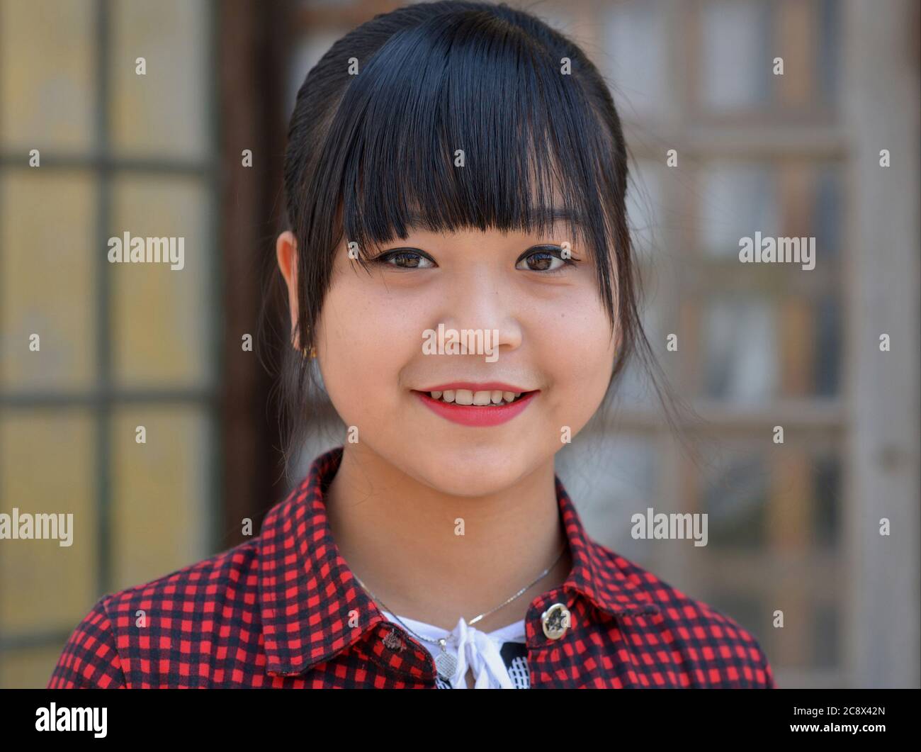 Pretty Burmese teen girl with bangs and cute chubby cheeks smiles for the camera. Stock Photo