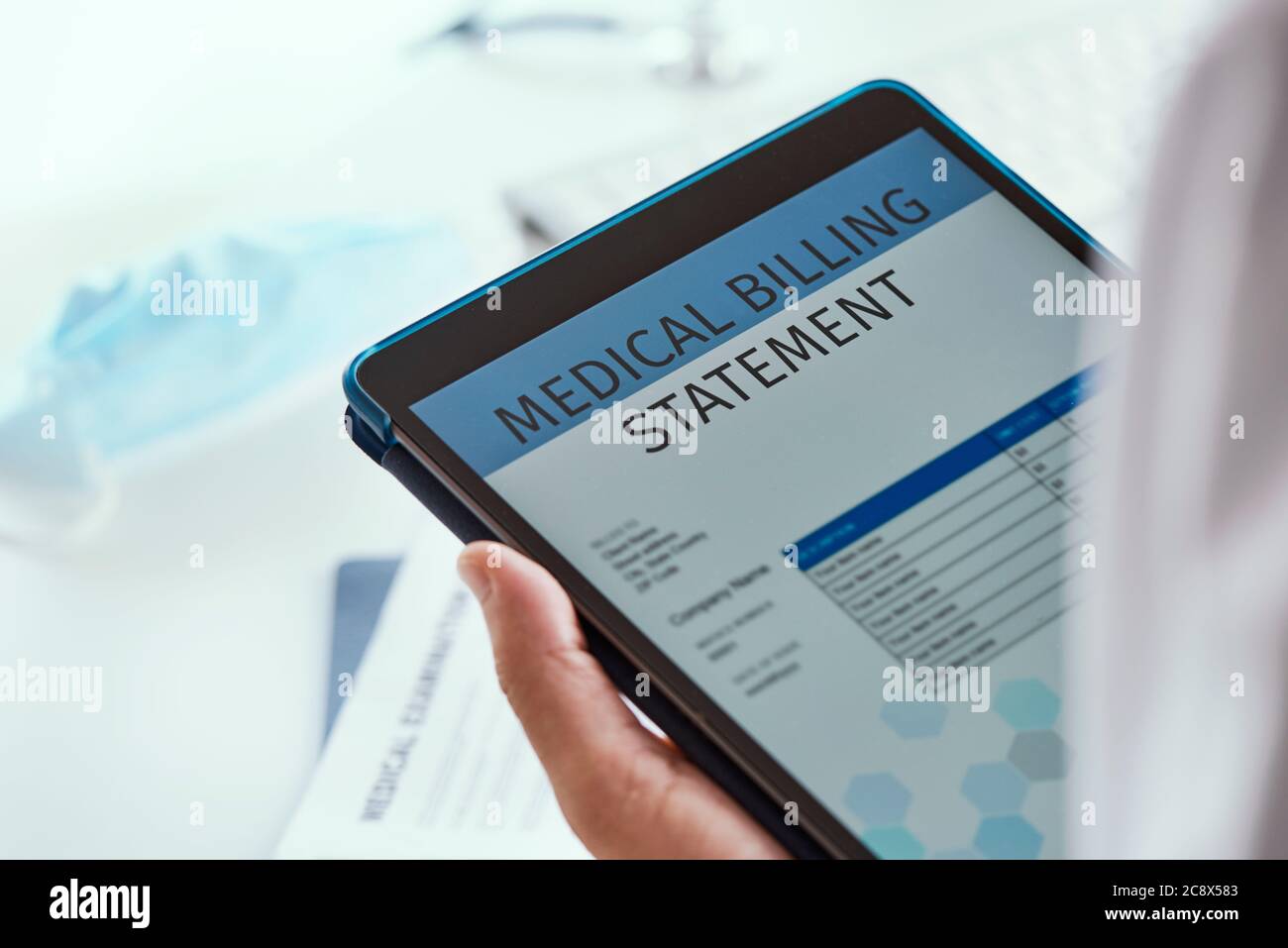 closeup of a caucasian doctor man, at his office desk, checking a medical billing statement in a digital tablet Stock Photo