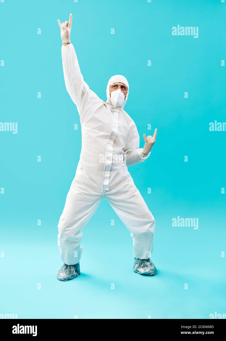 Full lenght portrait of happy doctor in PPE suit celebrating his success with winner gesture and hands up on blue background. victory, triumph and emo Stock Photo