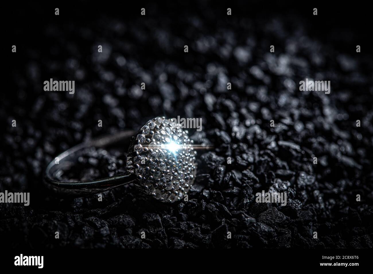 Silver ring with stones on black coal background Stock Photo