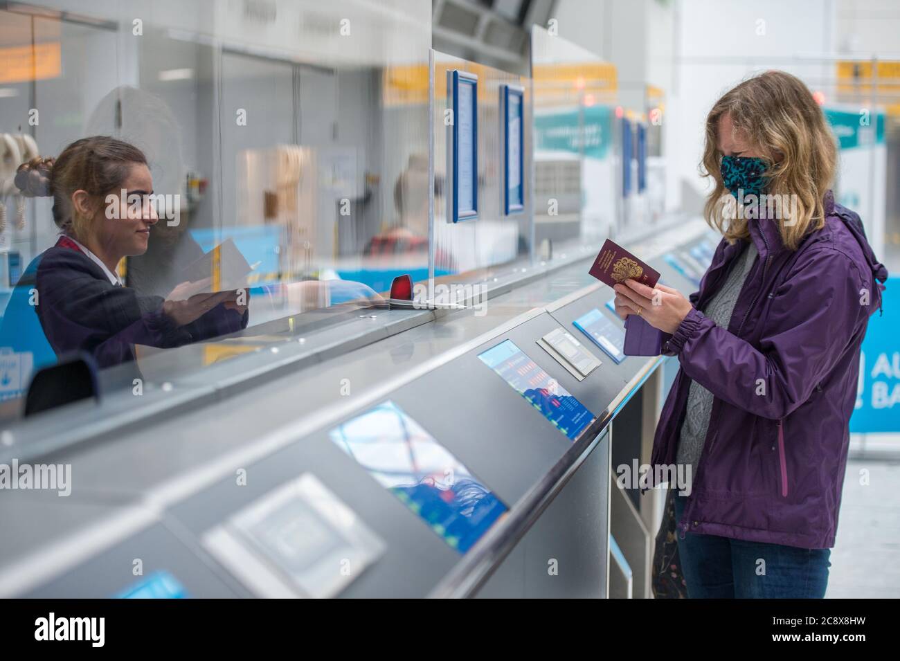 Glasgow, Scotland, UK. 27th July, 2020. Pictured: A passenger checks in for their flight at the newly adapted desks which have clear perspex screens to protect airport workers and maintain social distancing. Inside Glasgow Airport's terminal 1. The Scottish Government announced as from 00:01 this morning that all incoming flights from Spain into Scotland would need a period of 14 days quarantine. Jet2 Airlines have operated a number of flights this morning and a further afternoon service to Tenerife despite the new travel restrictions. Credit: Colin Fisher/Alamy Live News Stock Photo
