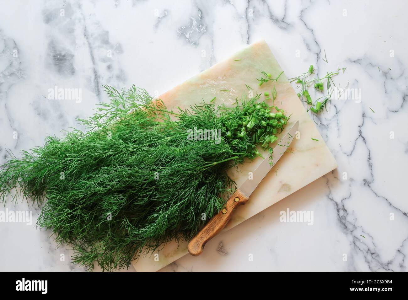 Cut fresh dills on a marble table, flat lay with a copy space Stock