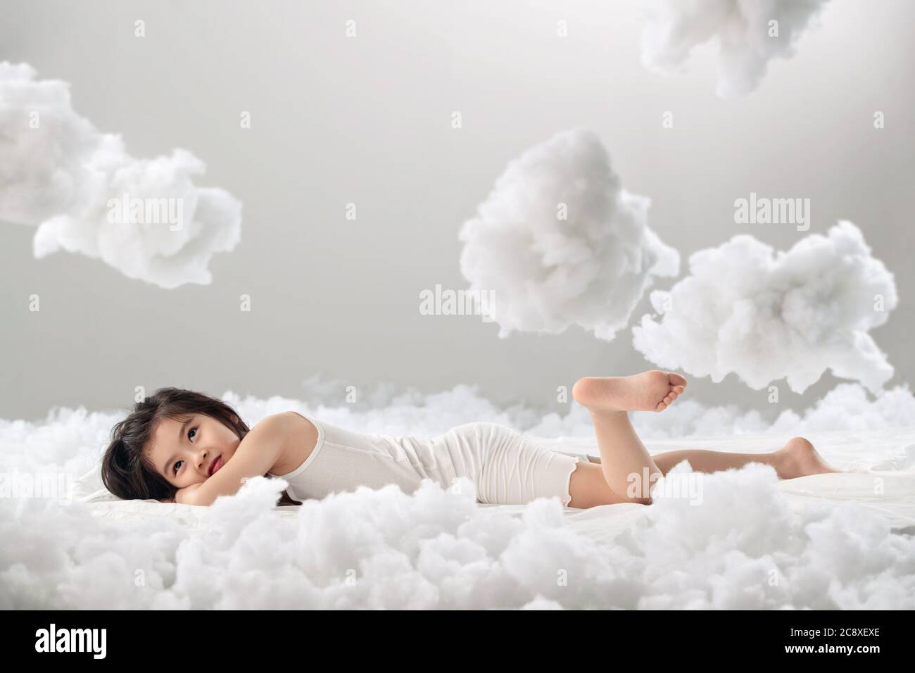 Lovely little girl lying on the cloud Stock Photo - Alamy