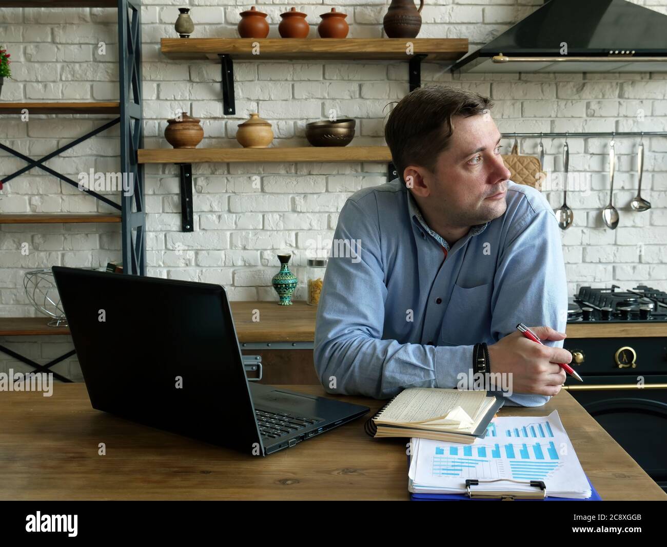 A man sits in the kitchen and works remotely. Stock Photo