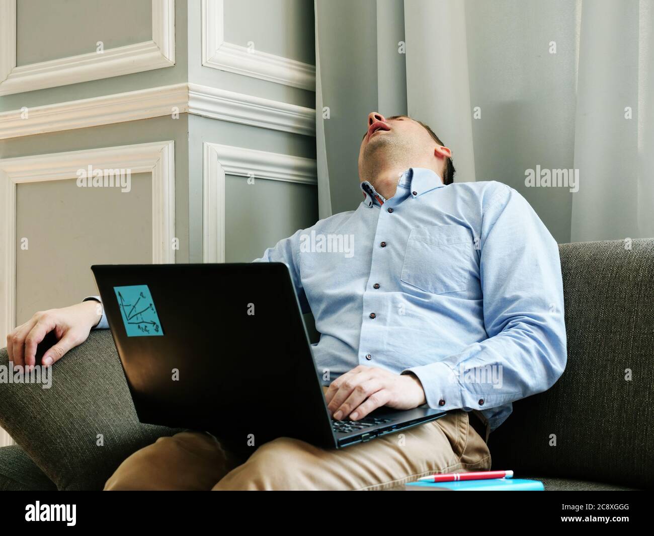 Tired man with chronic fatigue syndrome cfs sleeps with laptop. Stock Photo