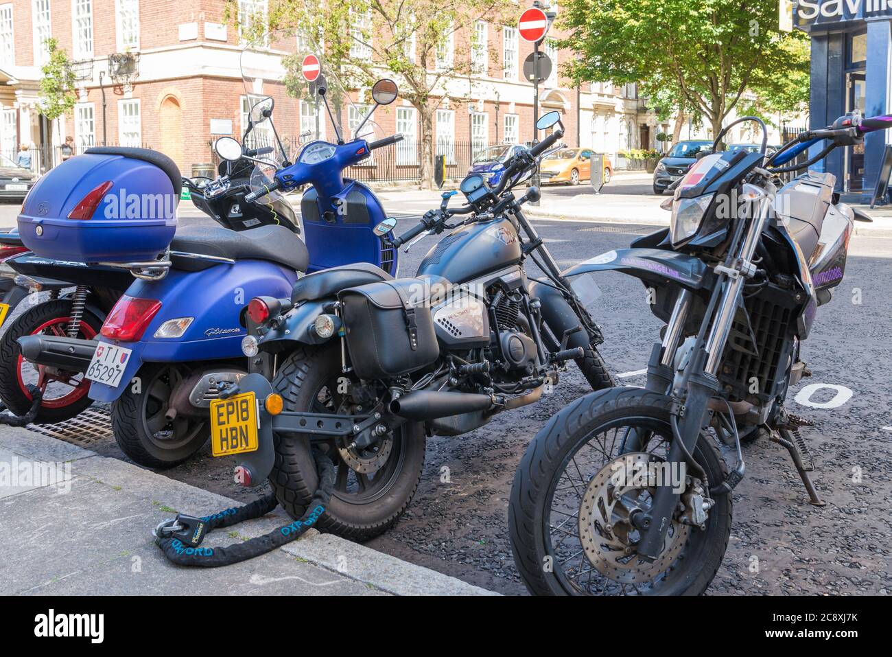 Motorbikes parked kerbside in a street parking bay, London, England, UK Stock Photo