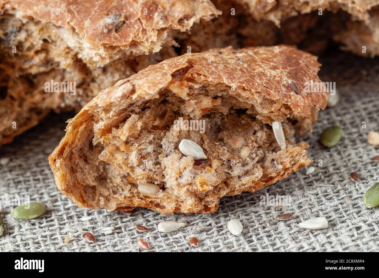 Uneven piece of multigrain bread, whole pumpkin seed, sunflower and flax seeds Stock Photo