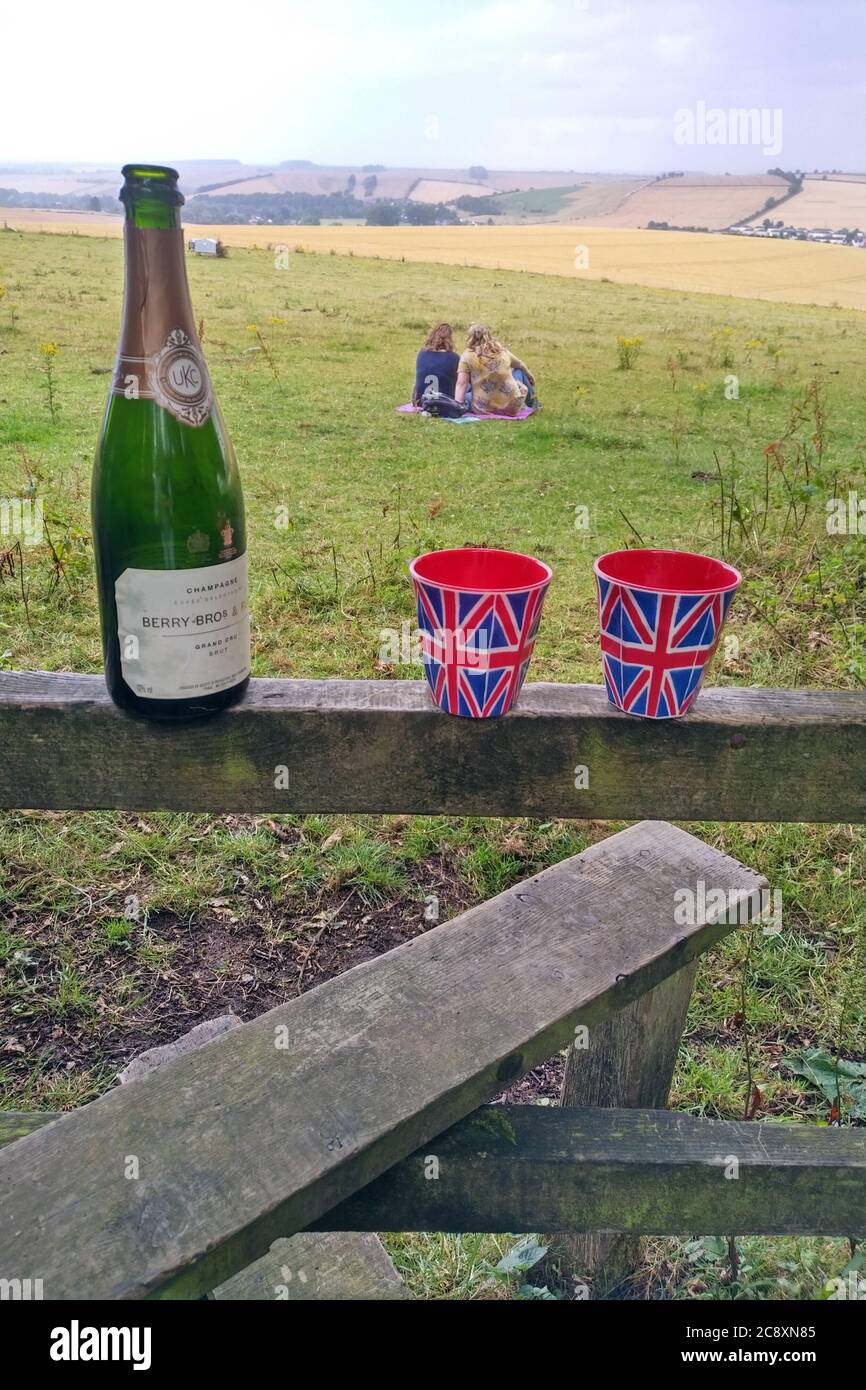 Birthday celebrations with Champagne and Union Flag cups on a country stile in the Wylye Valley near Wilton, Wiltshire UK 2020. Stock Photo