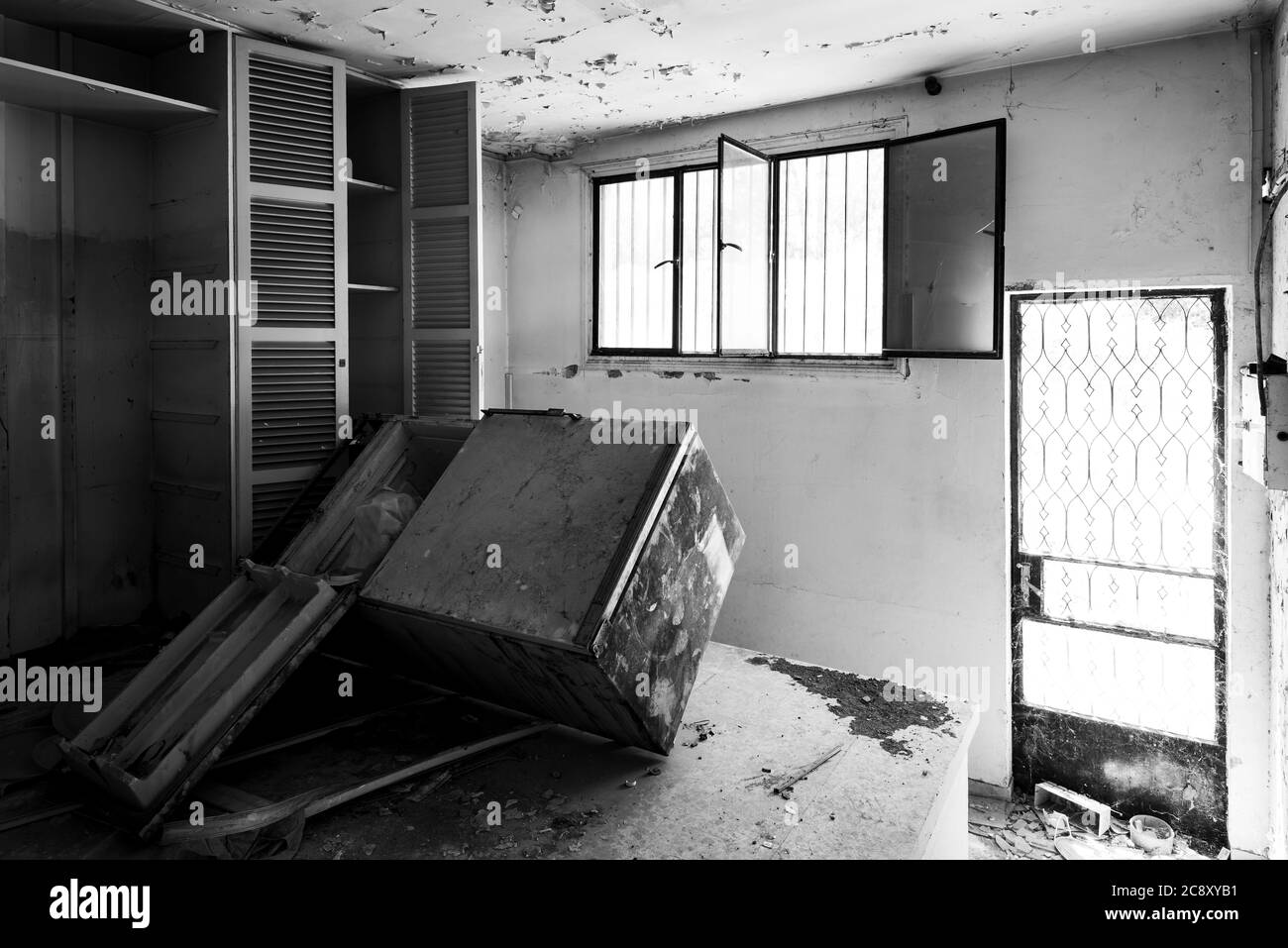 Interior of an old abandoned house kitchen with damaged wooden furniture. Monochrome photograph Stock Photo