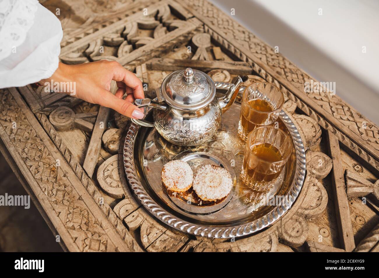 Woman hands serving traditional moroccan mint tea ceremony with cookies