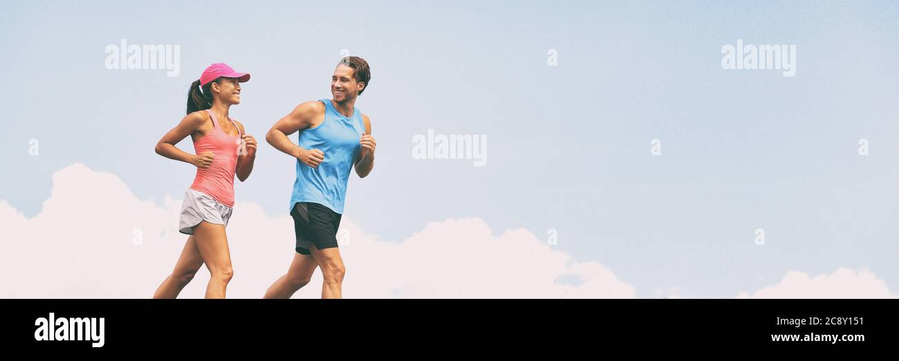 Healthy people fit active lifestyle couple running on sky background panoramic banner. Happy friends exercising together -training buddy Stock Photo