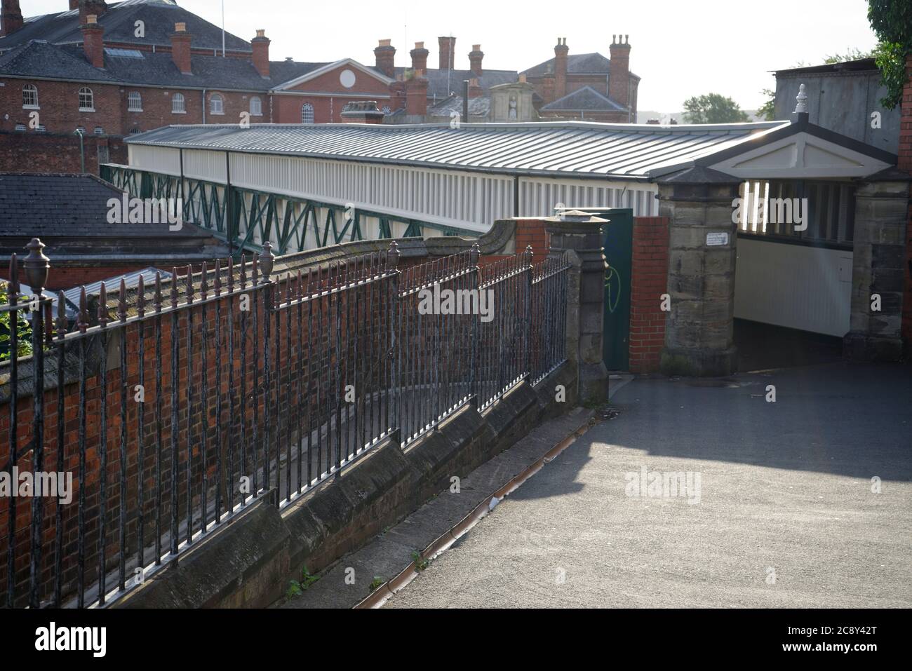 Covered walkway bridge over a railway. At Shrewsbury Station. Victorian metal railings in foreground. Stock Photo