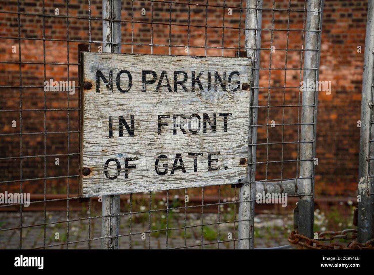 NO PARKING IN FRONT OF GATE. Old painted sign. Stock Photo