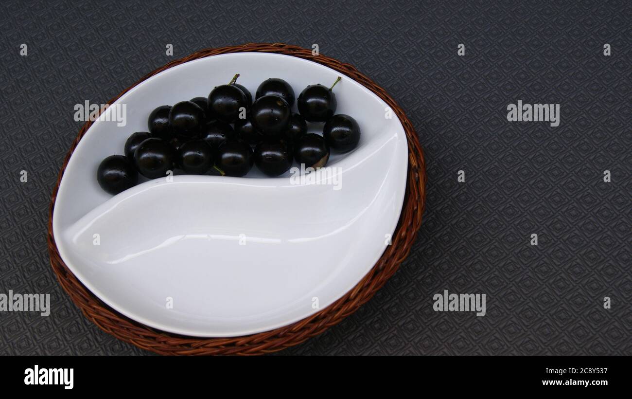 Jabuticaba fruit, fruit of Brazilian origin, belongs to the Myrtaceae family, on a white ceramic plate with wicker basket support, on a black backgrou Stock Photo