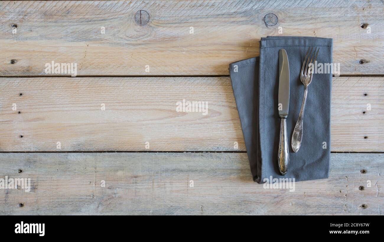 Cutlery and napkin on used look wooden background. Stock Photo