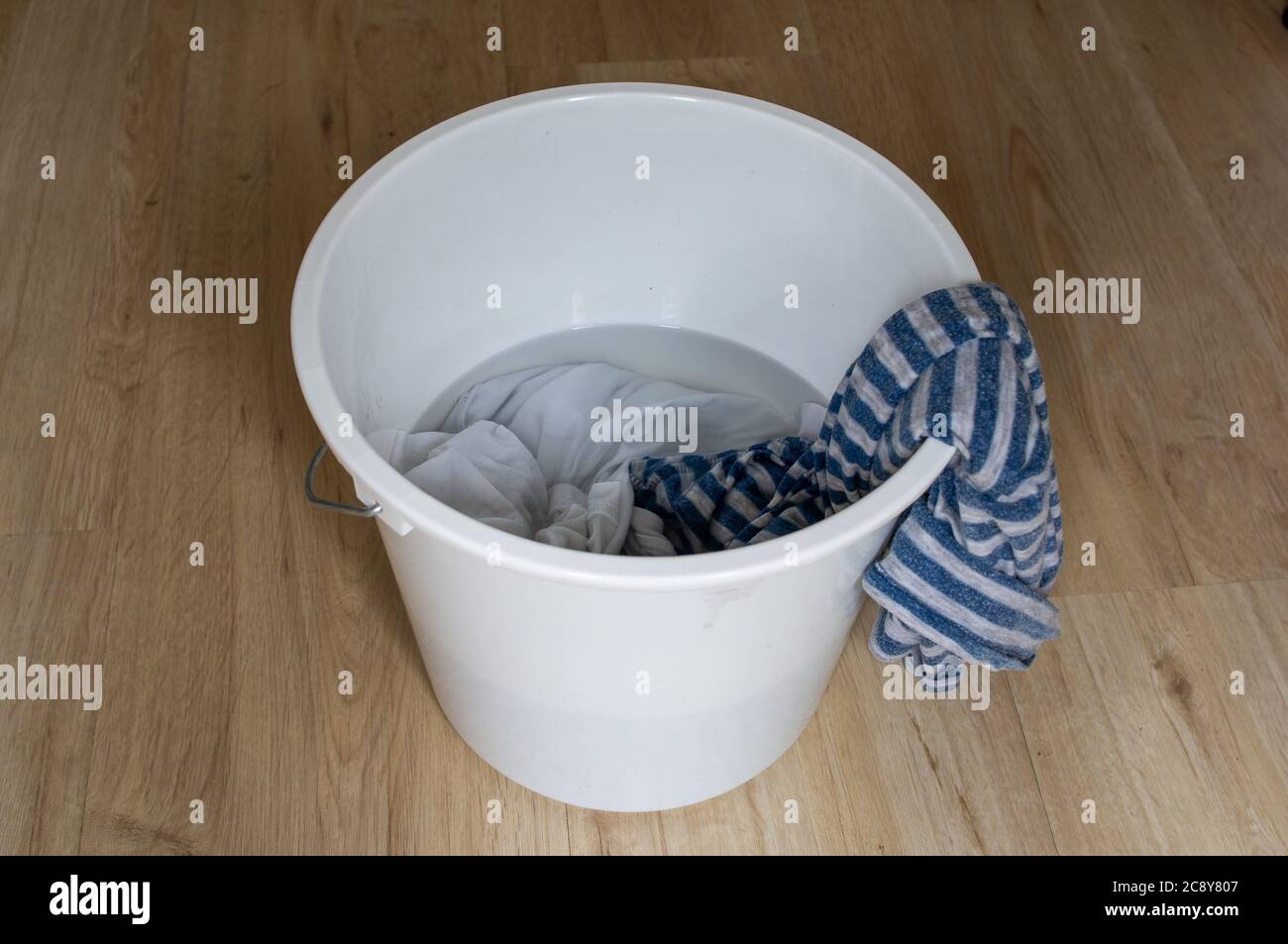 Hand wash. White plastic wash bowl with clothes in it Stock Photo