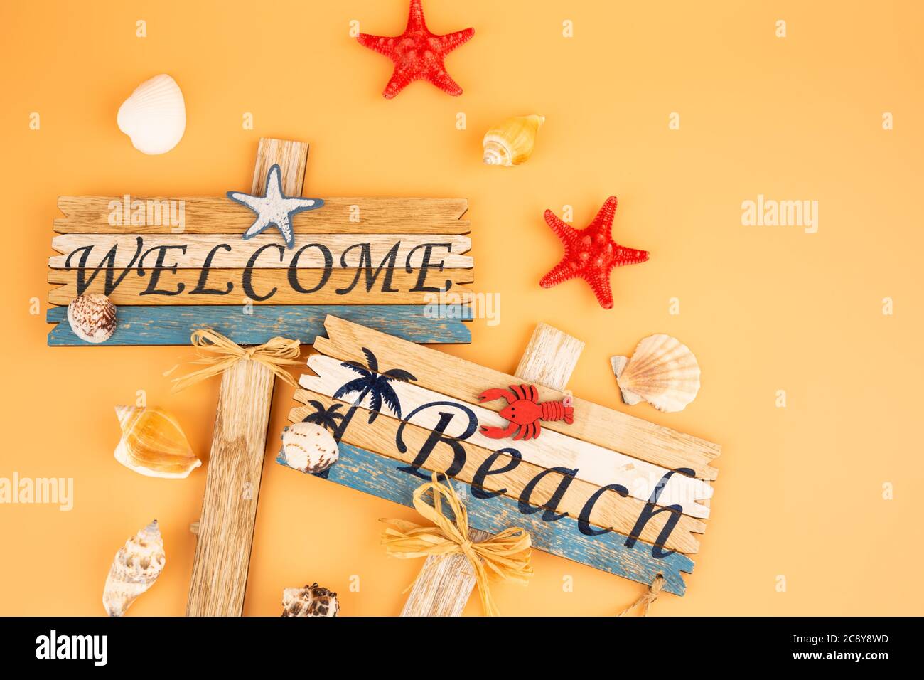 Wooden signs welcome beach, starfish and shells on yellow background. Stock Photo