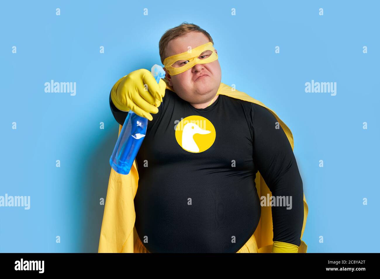 angry caucasian fat man in yellow costume applies detergent at camera, he is tired of dirt. cleaning concept Stock Photo