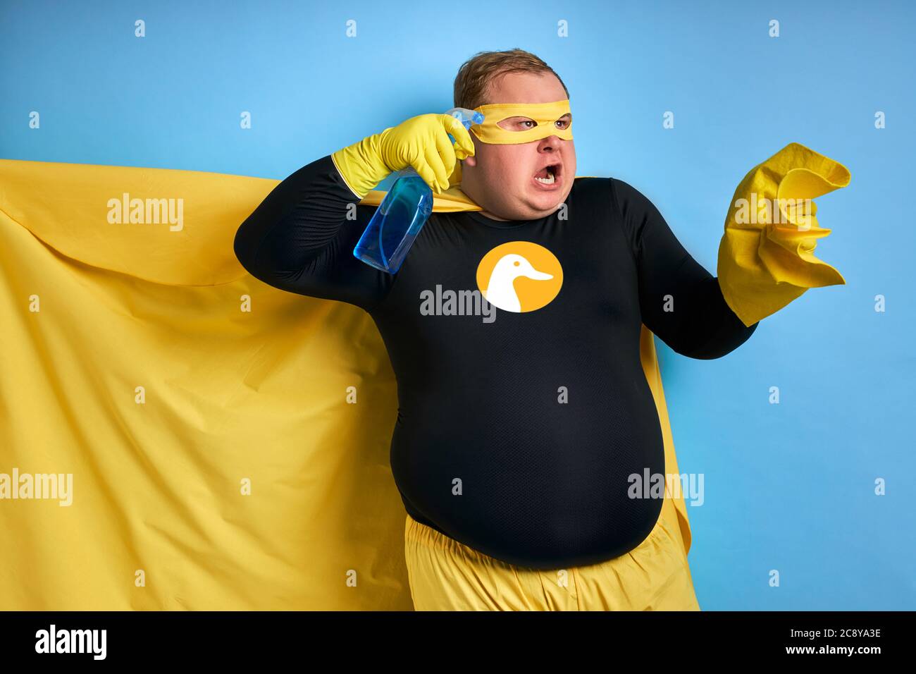 portrait of obese caucasian man with detergents and rag in hands isolated over blue background. amazing male going to wash and clean everything. clean Stock Photo
