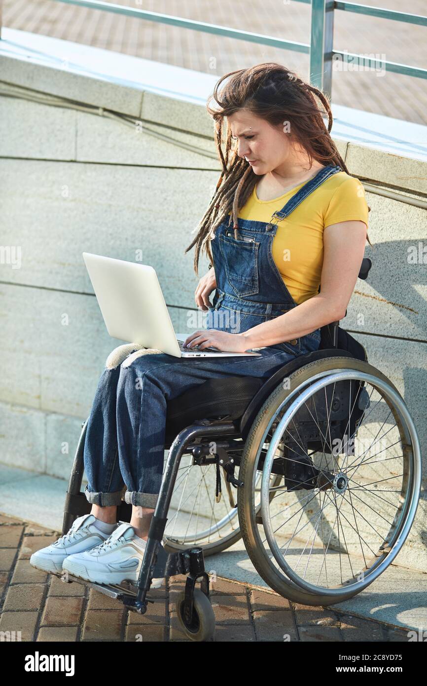 serious disabled girl looking for a job in the internet,reading e-book,doing shopping online . full length side view photo. Stock Photo