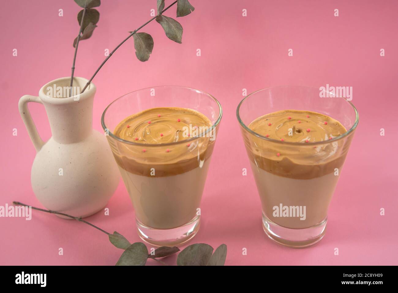 Two glasses of home made iced coffee with decorative white vase. Pink background Stock Photo